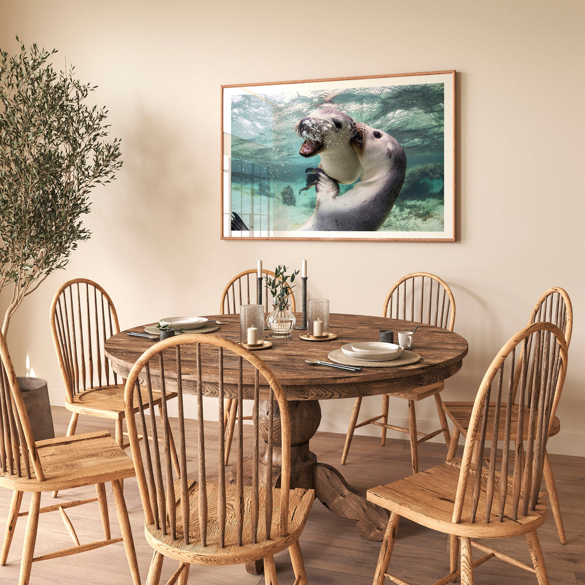 Room mockup above a dining table: Sibling love — two sea lion pups interacting underwater.