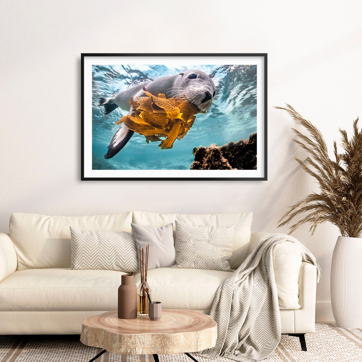 Room mockup above a sofa: Playtime — sea lion holding seaweed underwater.