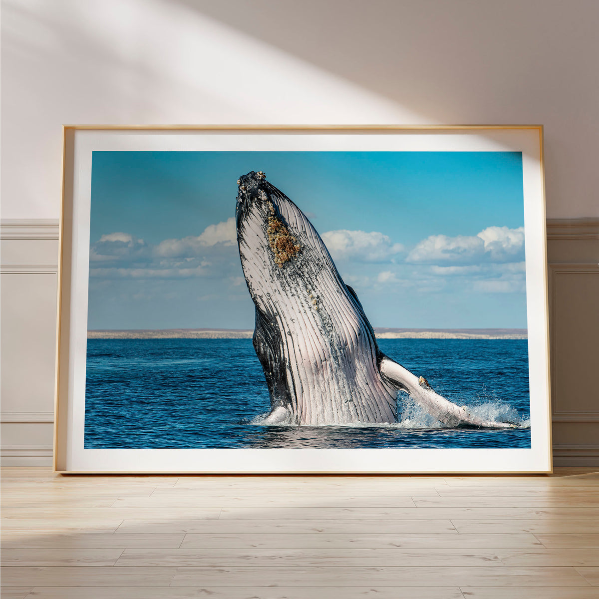 Styled preview in a wood frame on a floor: Humpback Highway — humpback whale breaching above the sea.