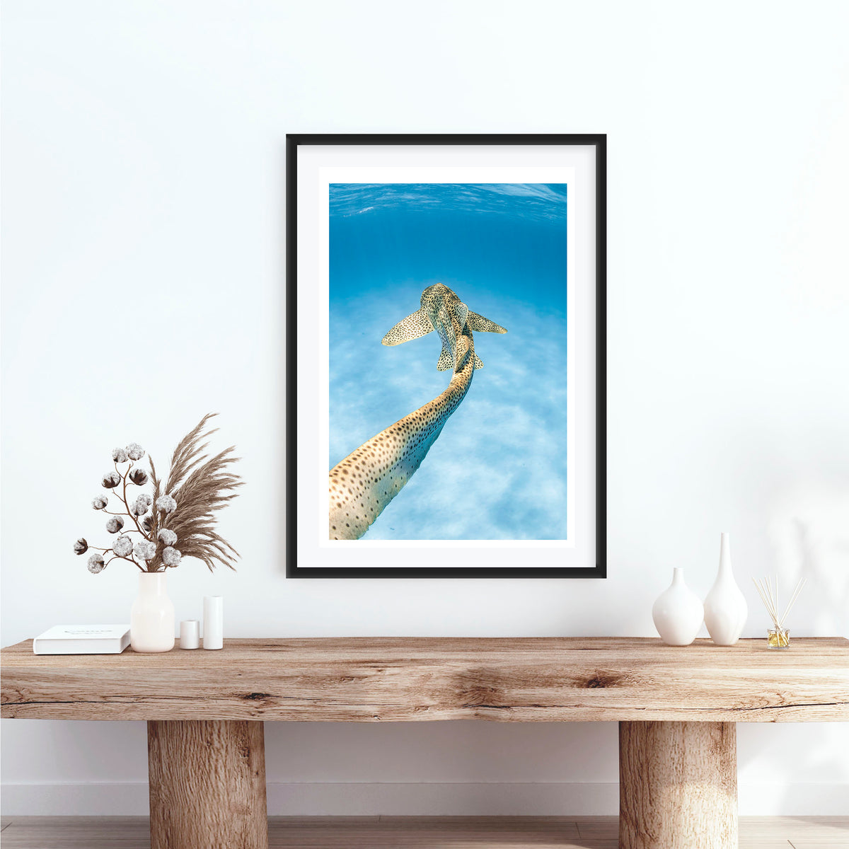 Room mockup above a console table: Leopards tale — leopard shark swimming above a sandy seabed.