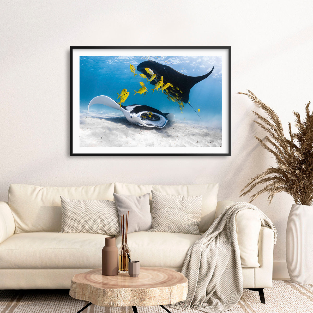 Room mockup above a sofa: Traffic — two manta rays and yellow fish above a sandy seabed.