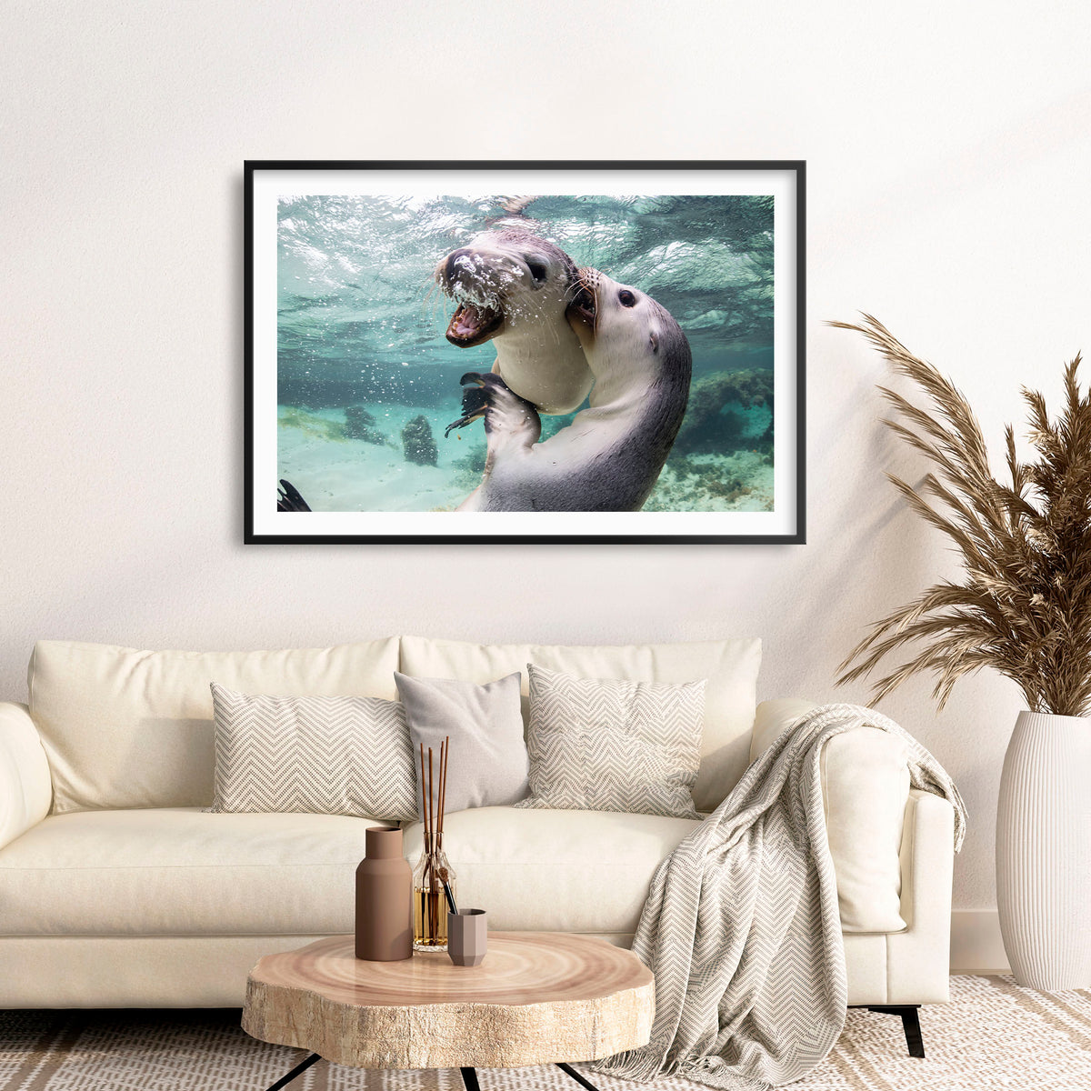 Room mockup above a sofa: Sibling love — two sea lion pups interacting underwater.